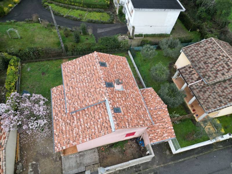 Artisan couvreur travaillant sur une toiture en tuiles à Alès