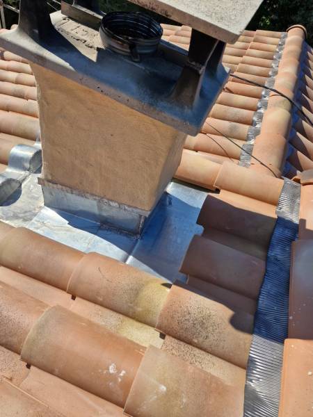 Ouvrier Masclaux Toiture réalisant des travaux de zinguerie sur une cheminée lors d'une rénovation complète à Nîmes.